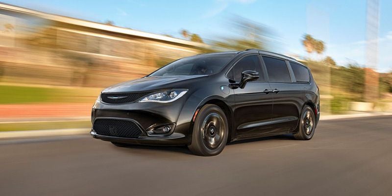 Black minivan with dark tinted windows, moving quickly down a blurred road, with a motion-blurred background.