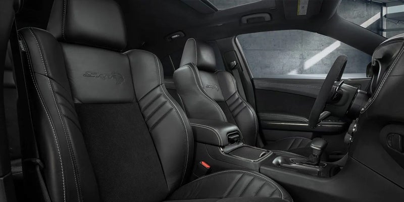 Black leather interior of a car, featuring two front bucket seats with white stitching and "SRT" embroidered on them.