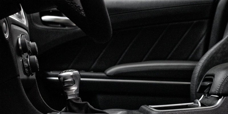 Inside view of a car, showing the gear shift, climate controls, door panel, and driver's seat.