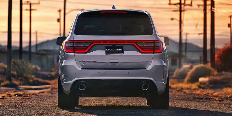 Rear view of a silver Dodge Durango SUV on a road at sunset, power lines in background.