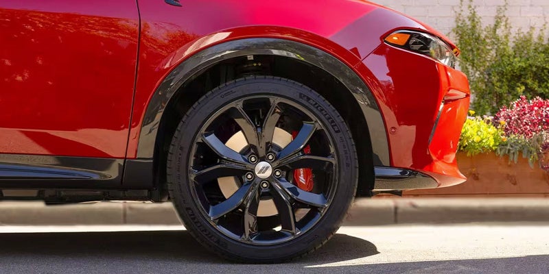 Front quarter view of a red SUV, showing its glossy black rim and red brake caliper.