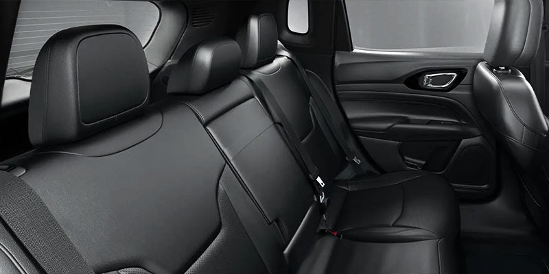 View of a modern car's interior, showing part of the black leather back seats and door panel.