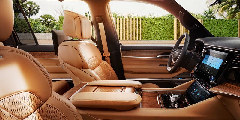Luxurious tan leather interior of a car, showing the dashboard, touchscreen, and front passenger seat.