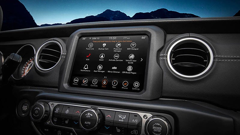 A car's dashboard at night, showing the infotainment system displaying apps like Travel Link and WiFi Hotspot.
