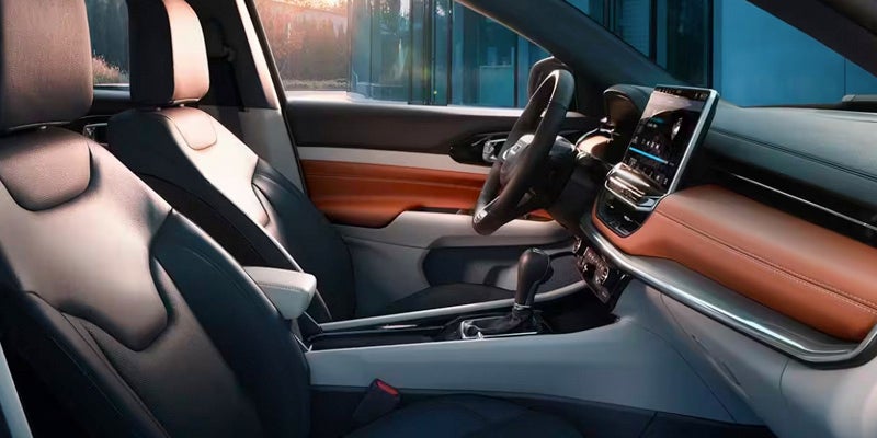 Interior view of a car with two-tone leather seats, infotainment screen, and brown dashboard accents.