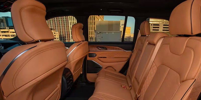 Interior of a modern SUV car, with light brown leather seats, and a view of city buildings through the windows.