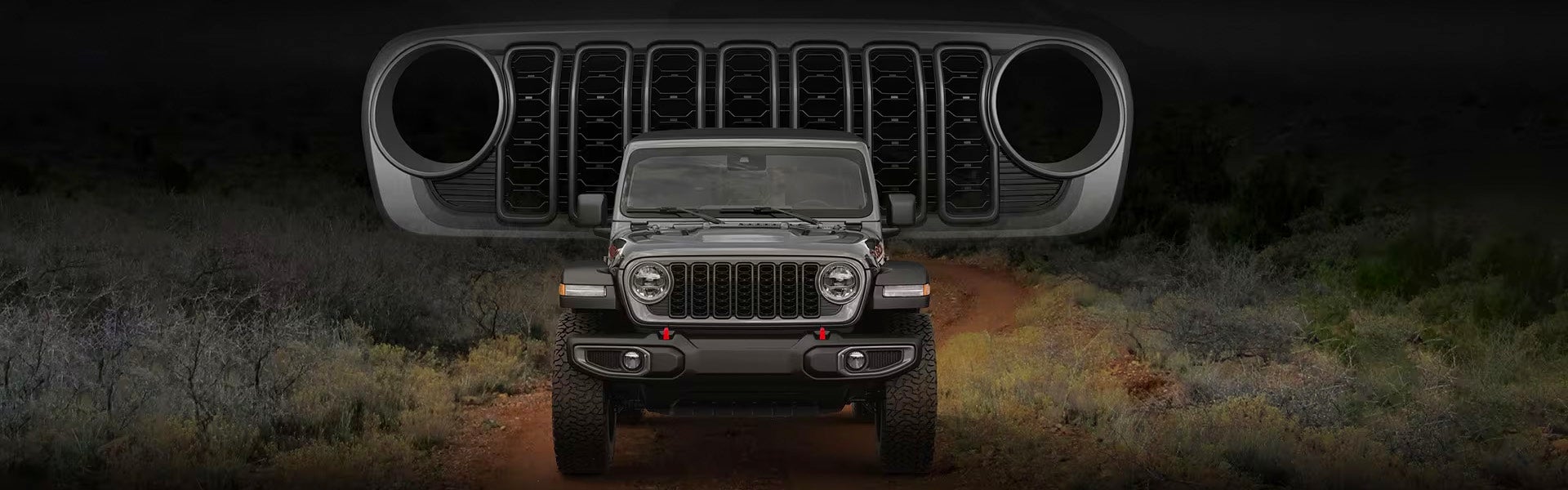 A gray Jeep Wrangler on a dirt road, viewed from the front, with a larger, floating Jeep grille above it.