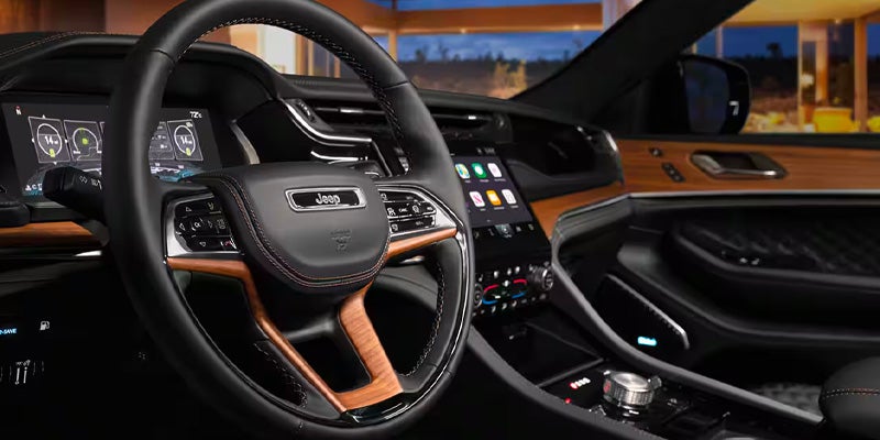 Luxury car interior from driver's seat, showing steering wheel, digital dashboard, and infotainment screen.
