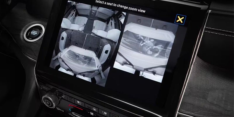 An in-car dashboard screen showing a split-view display of the vehicle's interior, including a zoom on a sleeping baby.