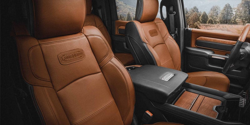 Tan leather truck interior with a "Longhorn" logo on the seats, black accents, and rich wood trim.