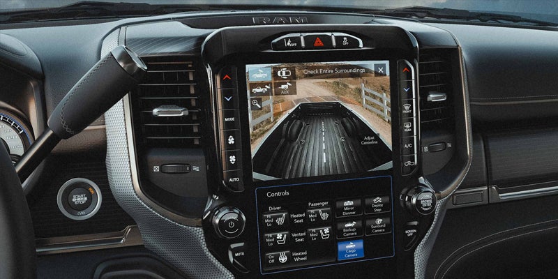 A Ram truck's dashboard features a large touchscreen displaying a rear cargo bed camera view and control options.