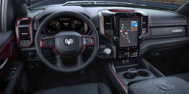 The interior of a black vehicle, with a large central screen displaying a map, and red accents on the dashboard.