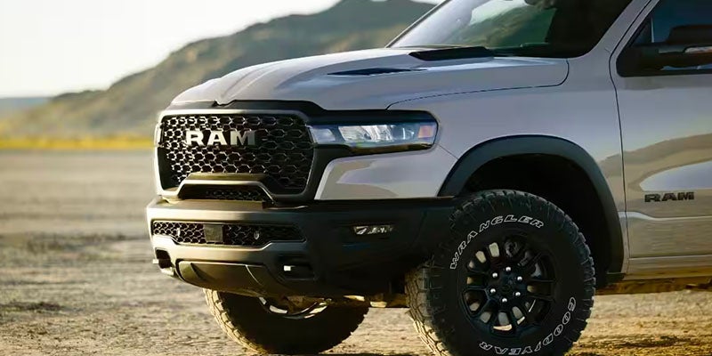 Front right view of a light gray RAM pickup truck with a black grille and off-road tires.